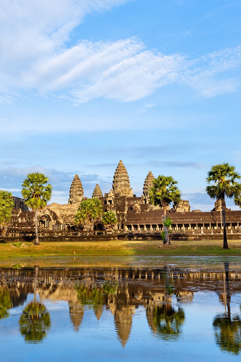 Iconic view of Angkor Wat temple reflected in water during golden sunset hour