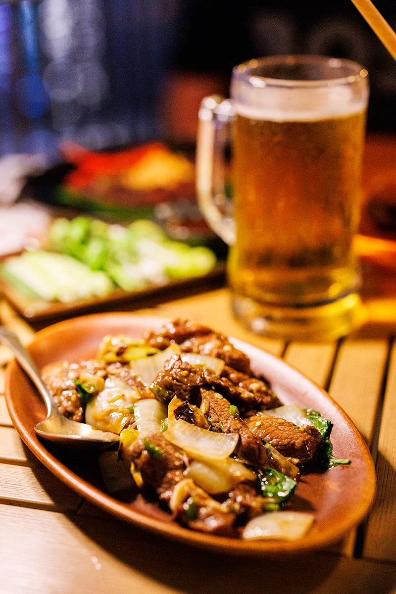 Thai beef dish with beer in background