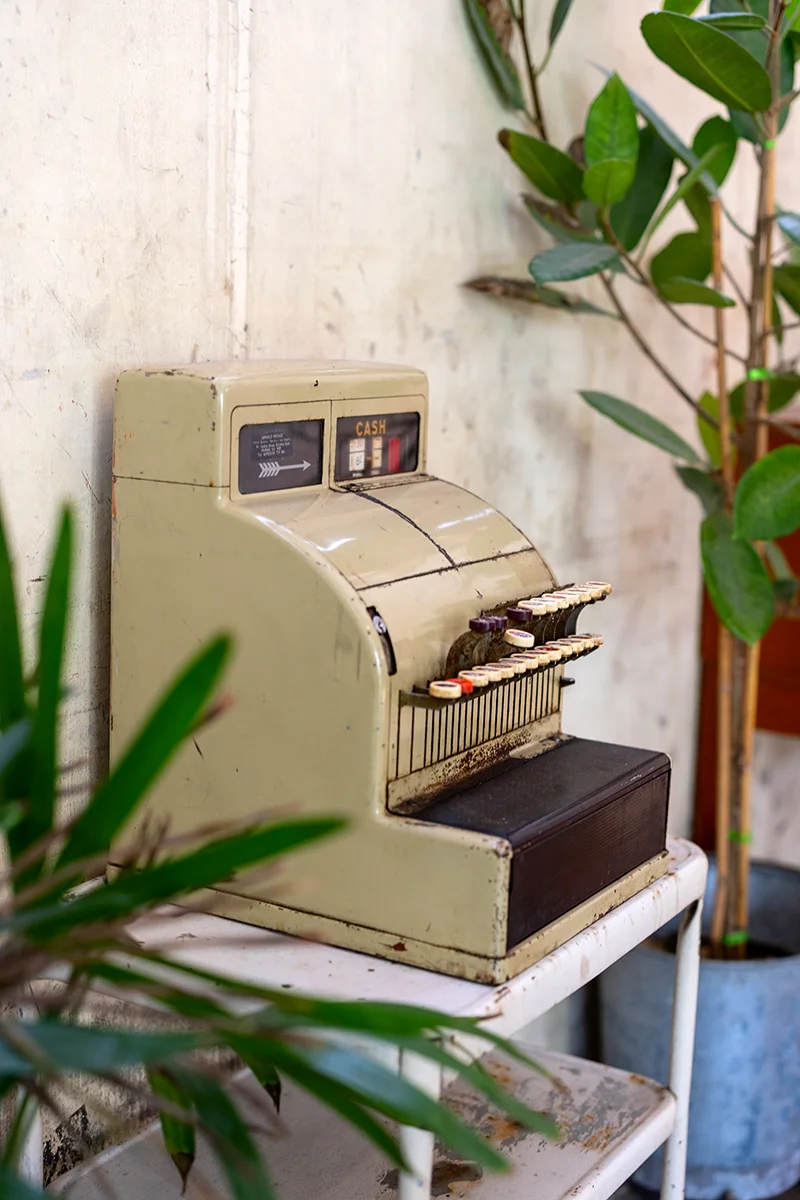 Vintage cash register beside plants - Piccolo Vicolo cafe in Bangkok