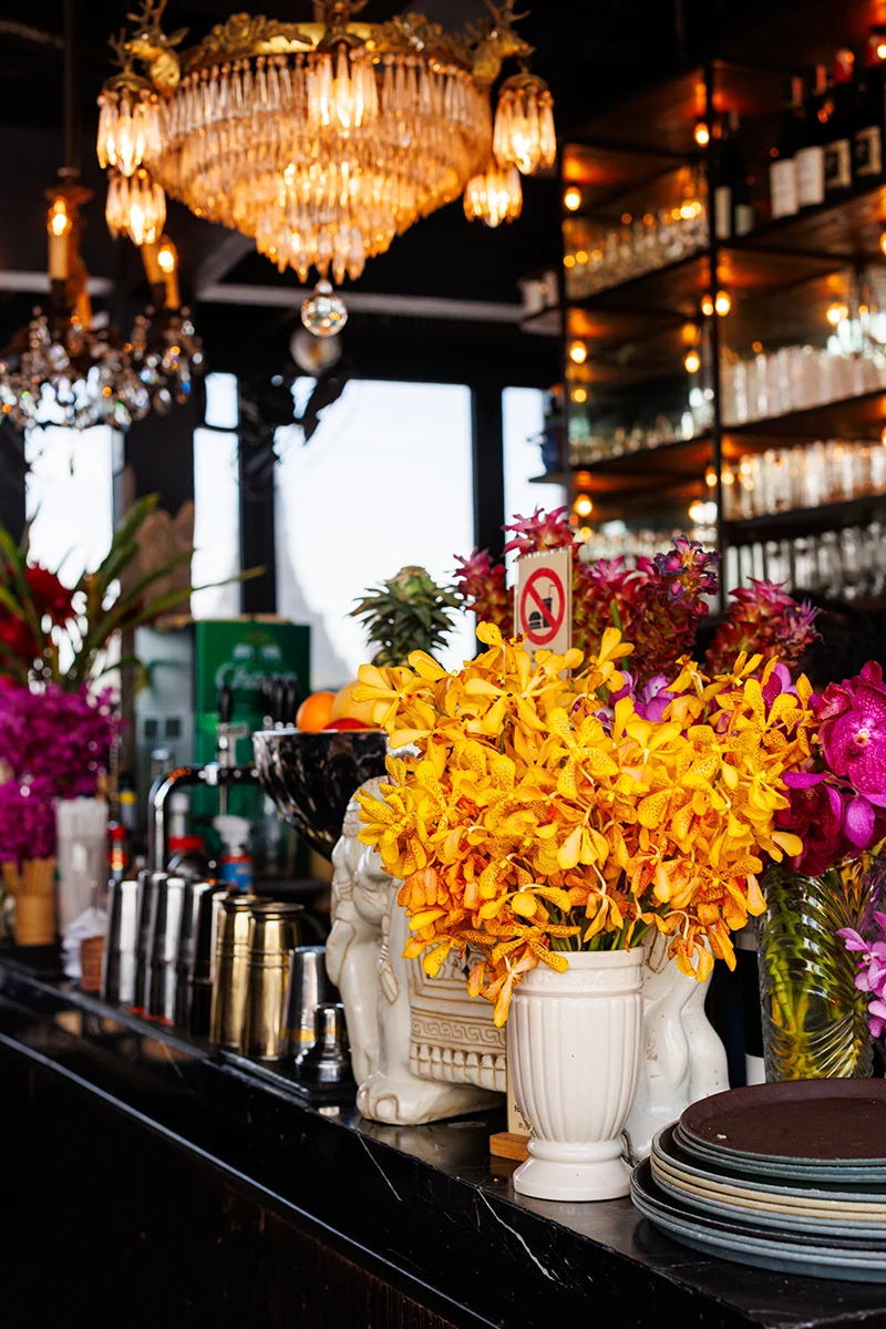 Vibrant flowers in stylish bar setting at Rongros restaurant in Bangkok