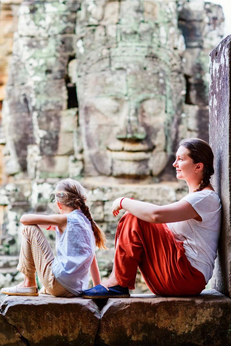 Family visiting Bayon temple in Angkor with iconic smiling stone faces