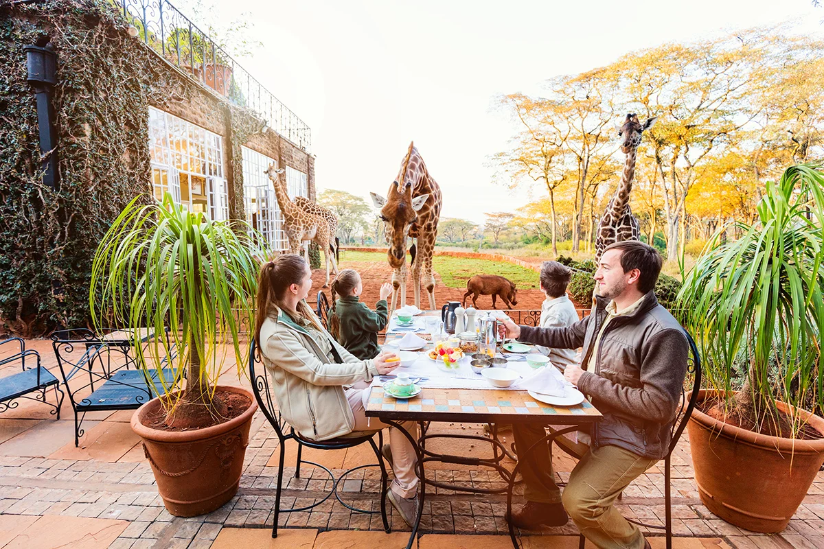 Family with children at an outdoor breakfast table at Giraffe Manor hotel in Nairobi
