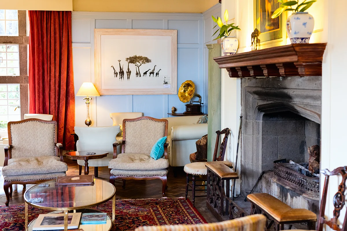 Elegant interior of common lounge area at Giraffe Manor hotel in Kenya featuring a cozy fireplace, classic furnishings, and colonial-style décor