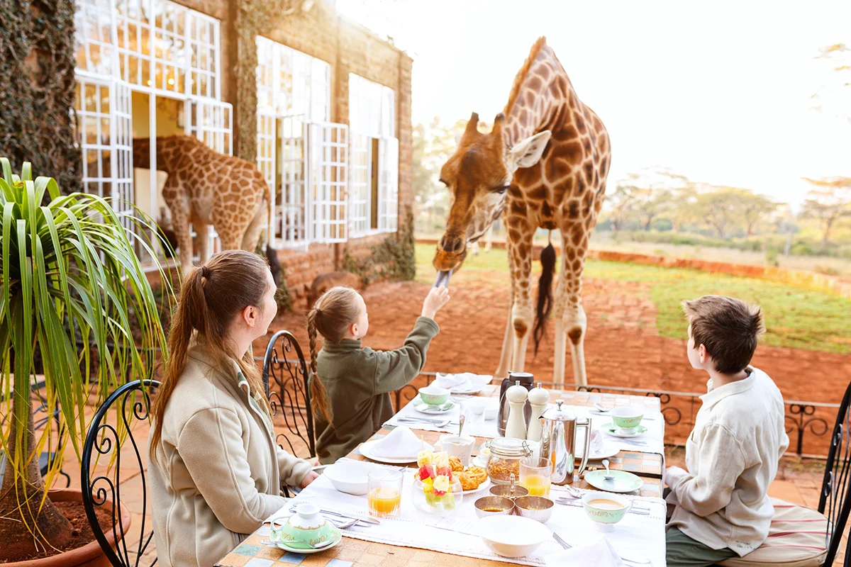 Family with children at an outdoor breakfast table at Giraffe Manor hotel in Nairobi