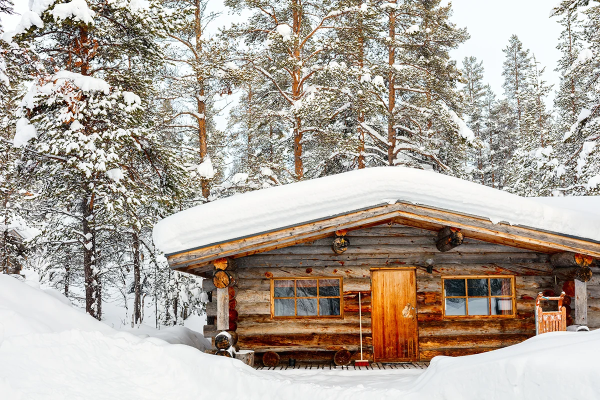 Log cabin surrounded by snow-covered trees in the forest at Kakslauttanen Arctic Resort in Finland