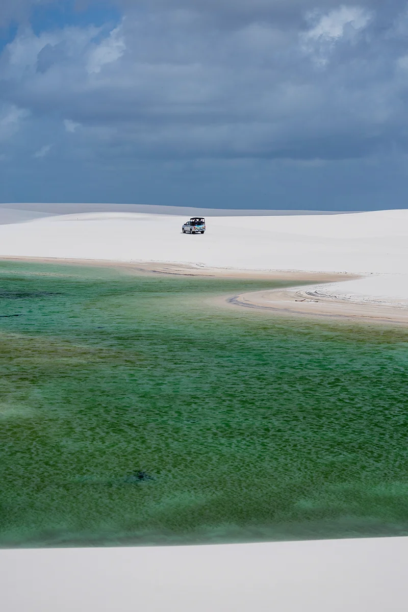 Vehicle near green lagoon in dunes
