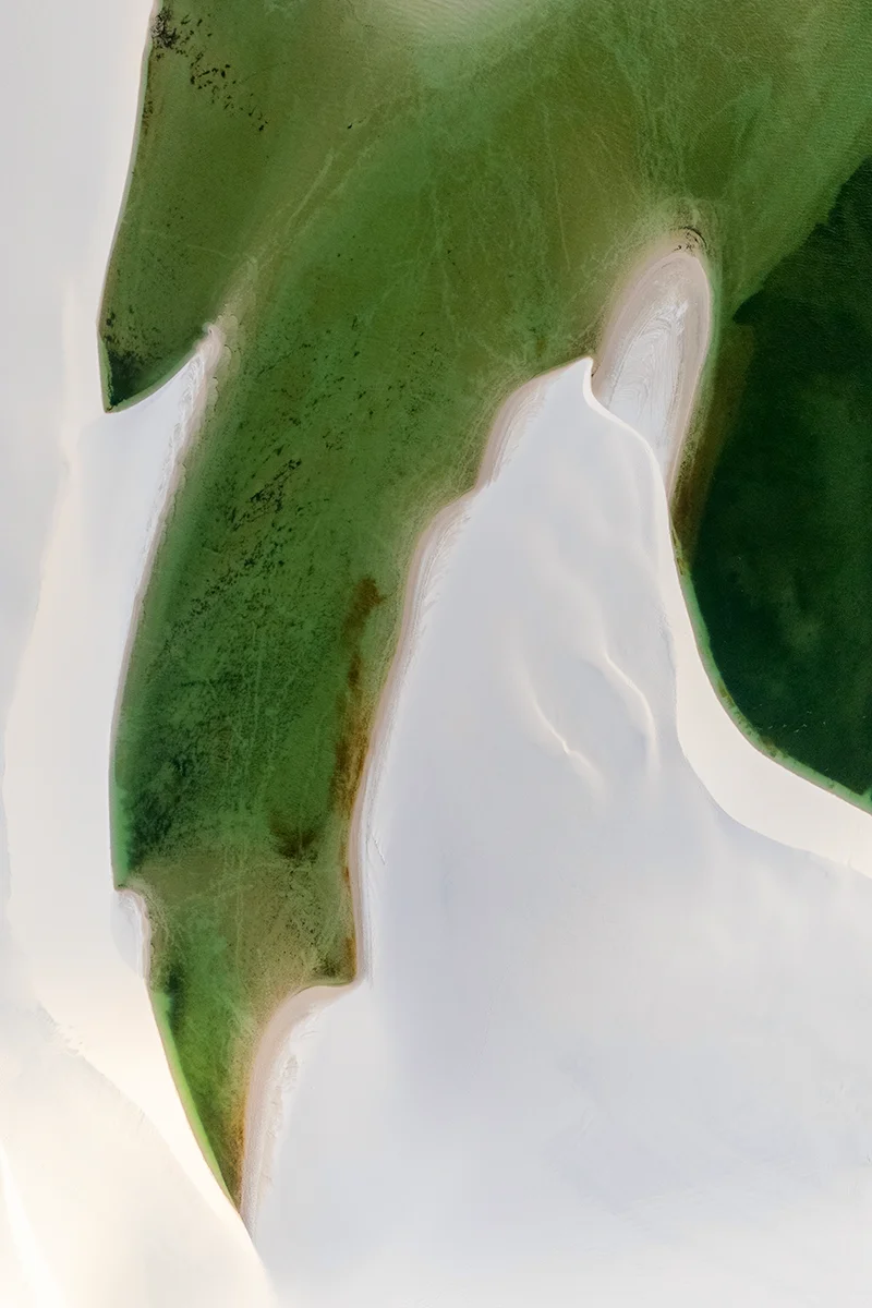 Aerial view of green lagoon and white sand dunes landscape