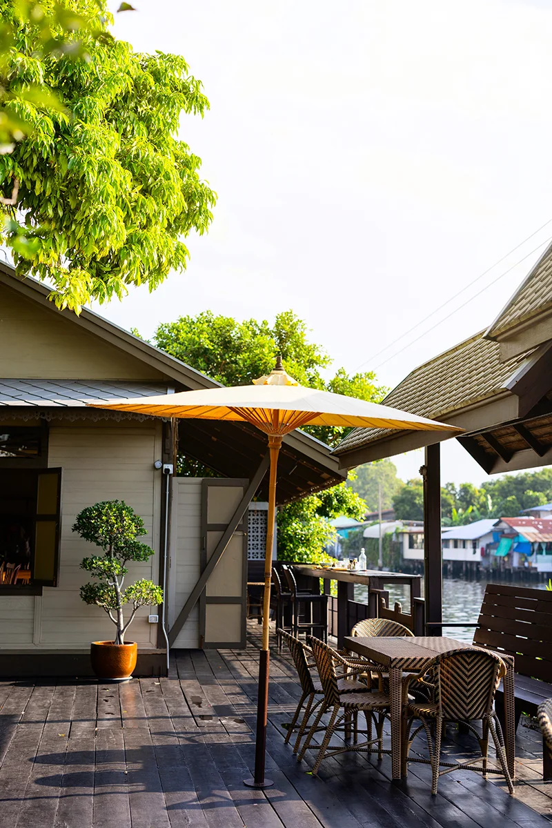 Outdoor seating by the water at Neil Niwas hotel in Bangkok