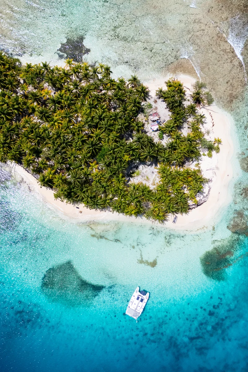 Catamaran near tropical island with clear blue waters
