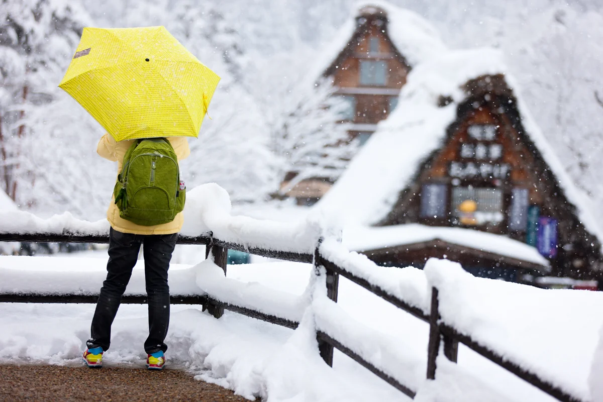 Tourist with yellow umbrella enjoying view of Shirakawa-go village