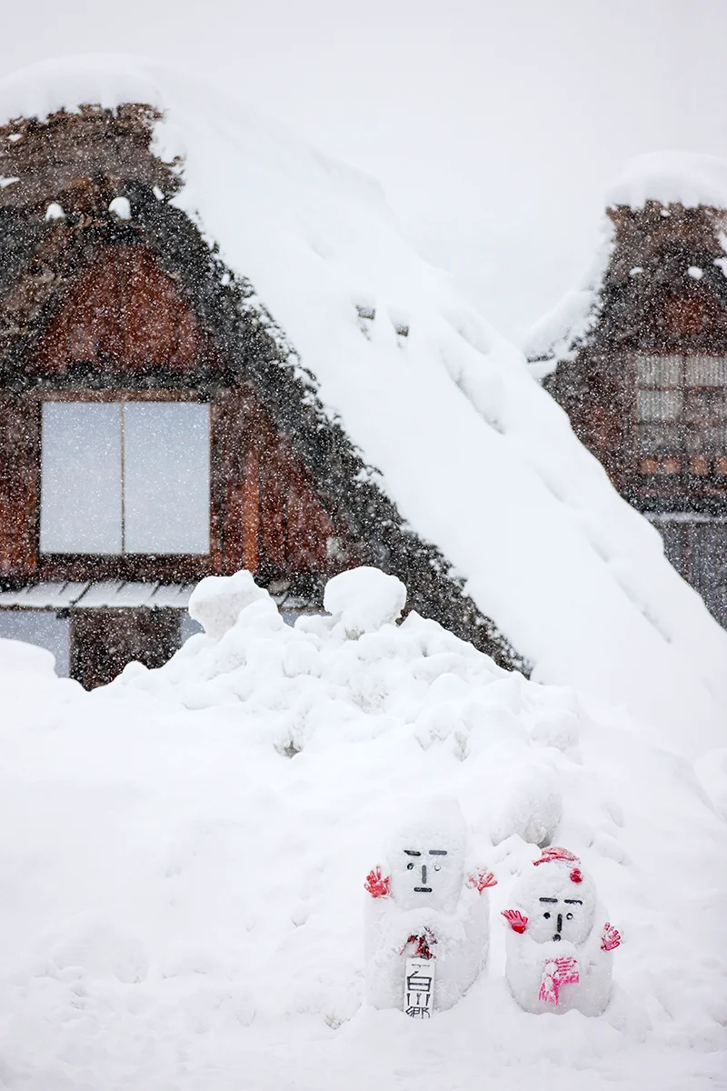 Snowy landscape with traditional houses and snowmen in Shirakawa-go in Japan