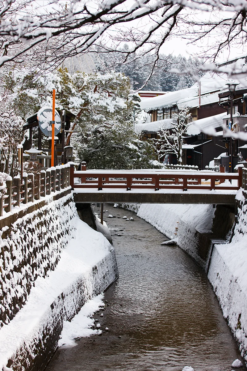 Snowy Enako River riverbank with wooden bridge in Takayama Japan