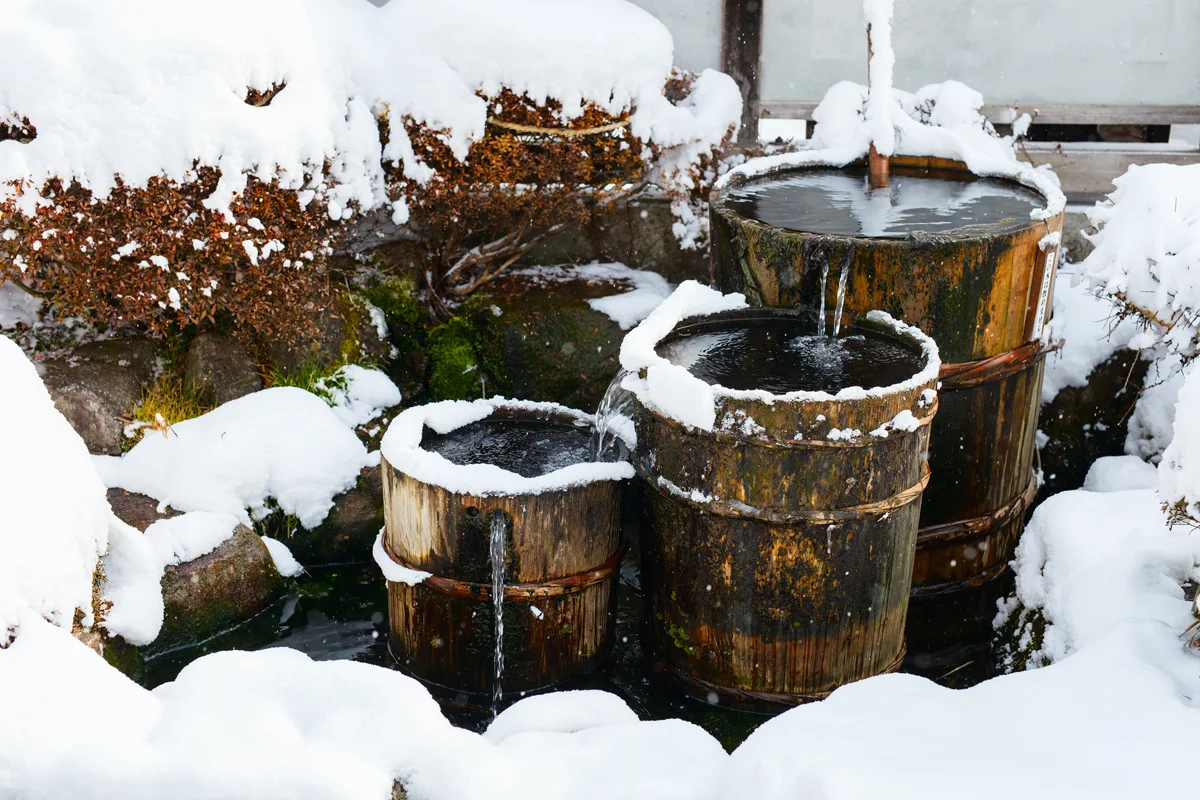 Snow-covered wooden water barrels