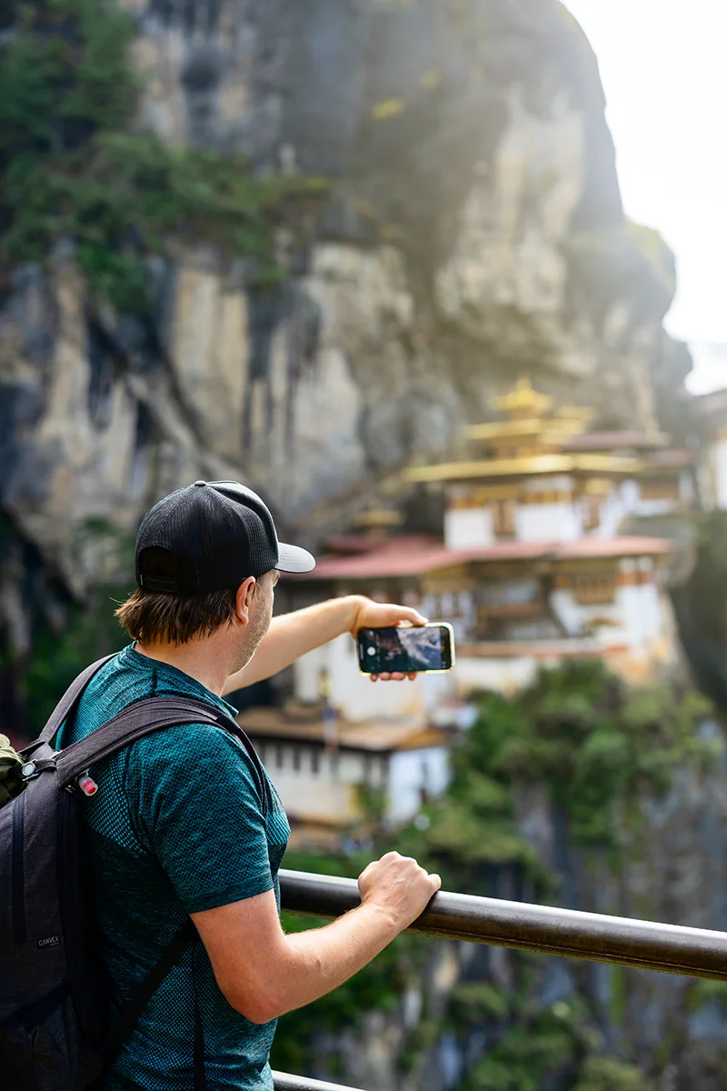 Man photographing iconic Tiger's Nest monastery on cliff